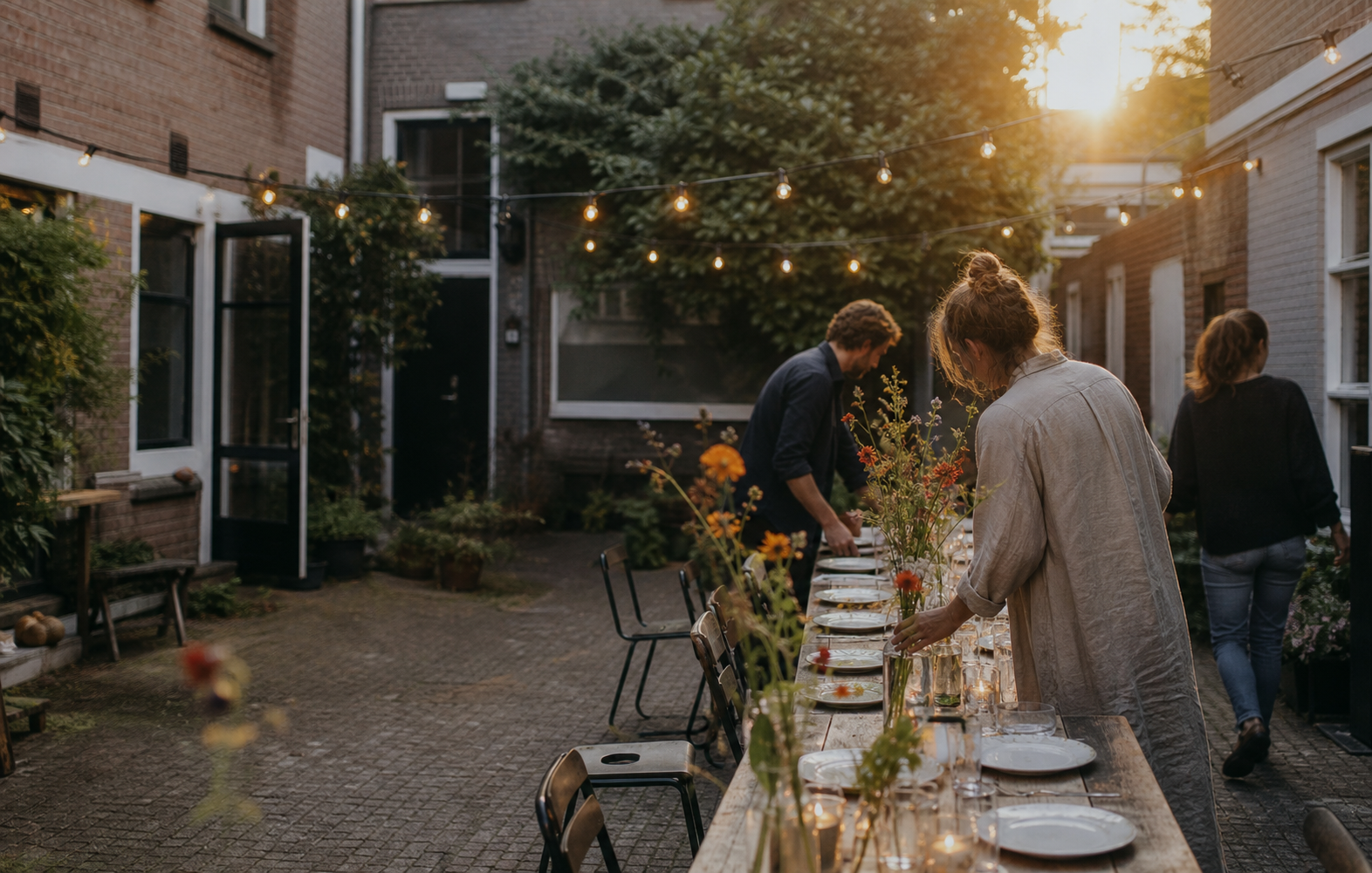 Buren dekken samen een lange tafel in een groene Nederlandse binnenplaats